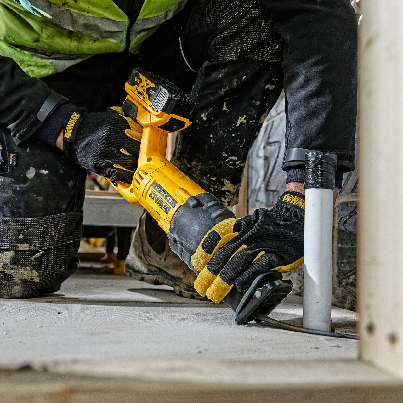 Dewalt DCS380N 18V XR Reciprocating Saw in use cutting plastic pipe on floor